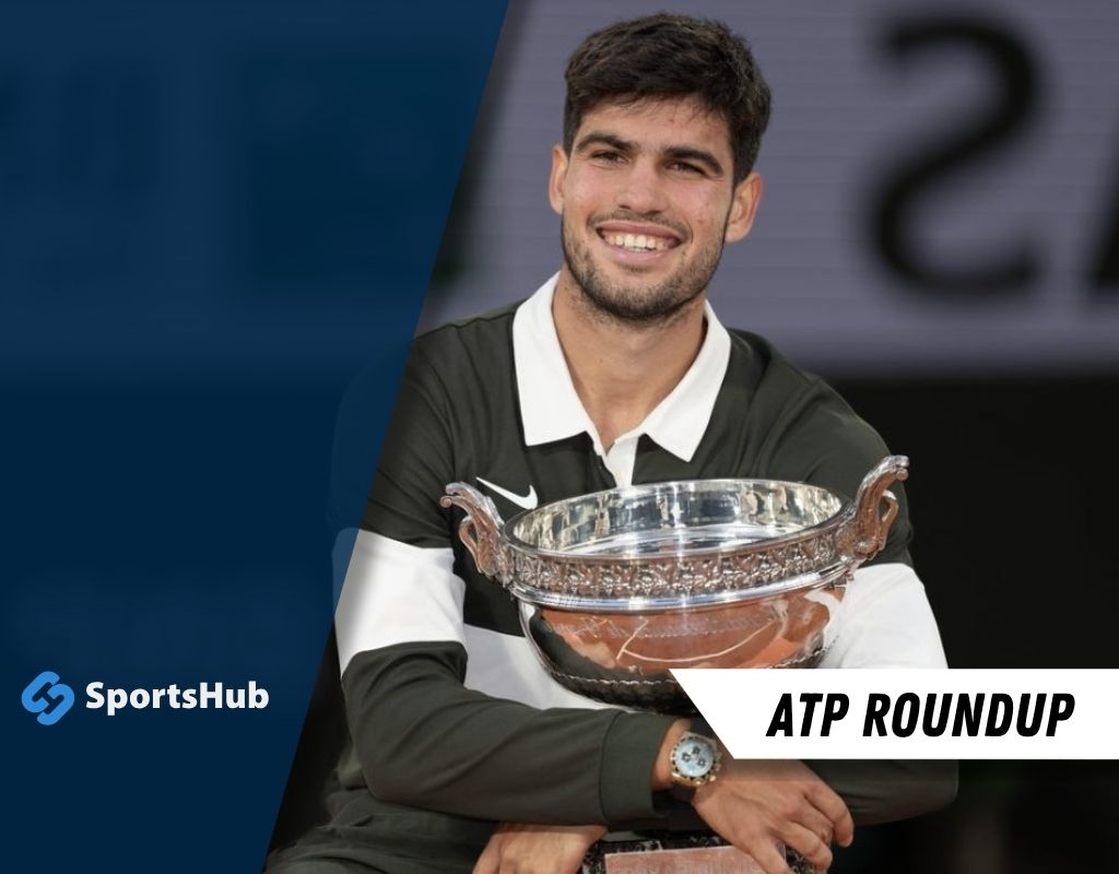 A tennis player in a black and white outfit proudly holds a silver trophy
